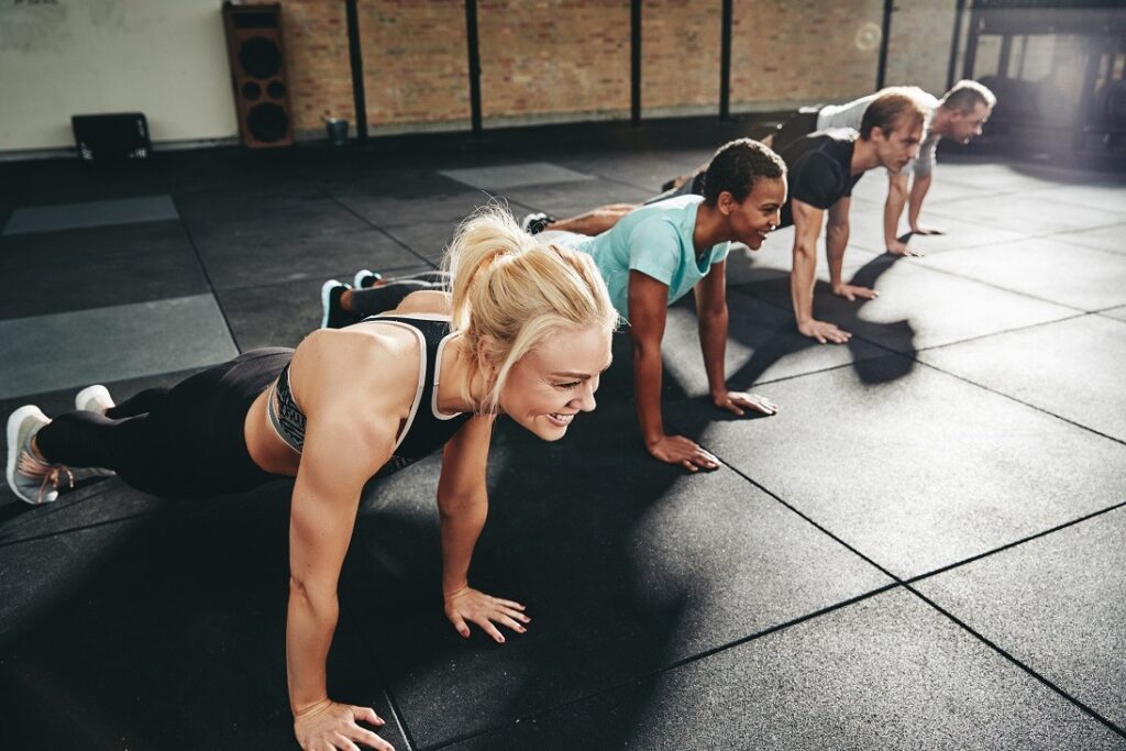Group of fit people doing push ups on a rubber flooring gym floor